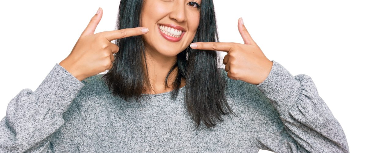 Beautiful asian young woman wearing casual clothes smiling cheerful showing and pointing with fingers teeth and mouth. dental health concept.